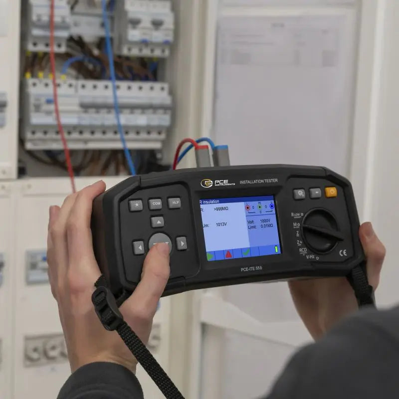 Μετρητής μόνωσης PCE Instruments PCE-ITE 55B σε χρήση, με έγχρωμη οθόνη και περιστροφικό διακόπτη μπροστά σε πίνακα