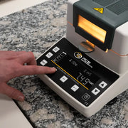Θερμοζυγός υγρασίας PCE Instruments PCE-MA 200 με φωτιζόμενο θάλαμο και ψηφιακή οθόνη, σε χρήση με πλήκτρα αφής