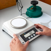 Ζυγός χαρτιού PCE Instruments PCE-DMS 1100 με στρογγυλή πλατφόρμα και ψηφιακή οθόνη, σε χρήση σε πάγκο